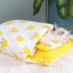 Cat peeking out from a yellow and white patterned blanket with crowns on a fluffy surface.