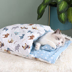 Cat lying on a patterned blanket with cartoon animals on a soft surface.
