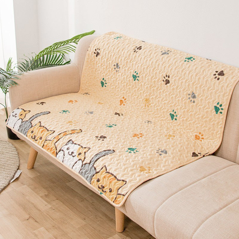 Beige sofa with a cartoon cat patterned throw blanket in a living room setting.