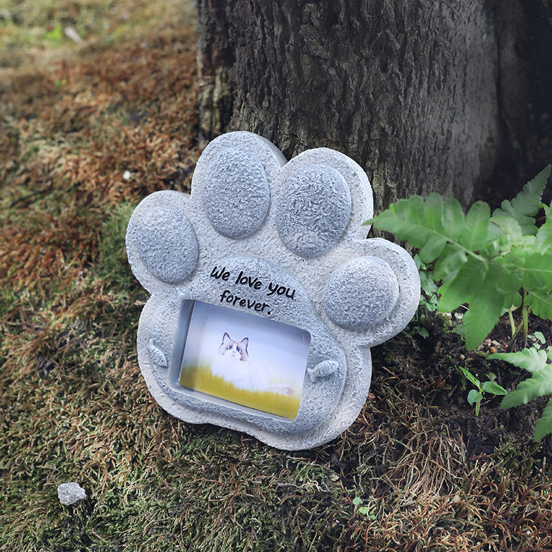 Paw-shaped memorial with 'We love you forever' text in a natural setting.