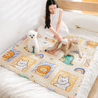 Woman playing with two dogs on a colorful quilt with cartoon designs.