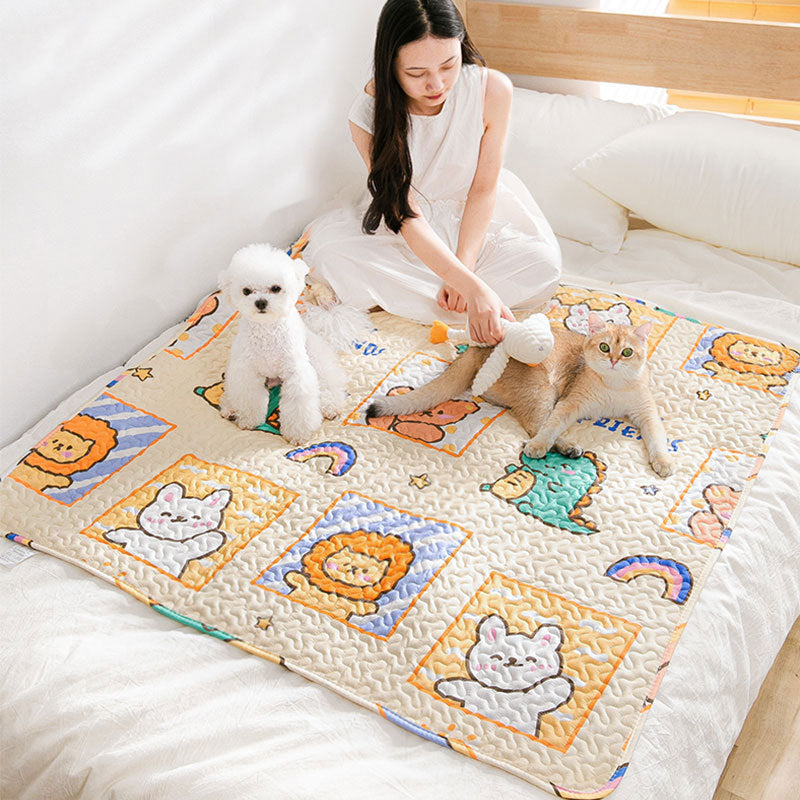 Woman playing with two dogs on a colorful quilt with cartoon designs.
