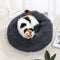 A pet bed in a round shape with a brown color, where a white cat is resting inside.