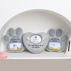 Three paw-shaped photo frames on a shelf with engraved text and small pictures inside.