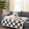 White dog on a checkered pet bed in a living room